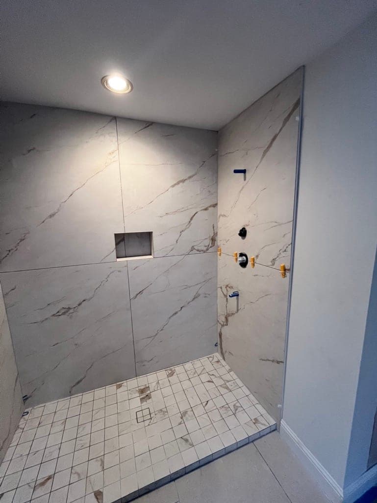 Walk-in shower in white marble-look large-format porcelain with a niche, before grout