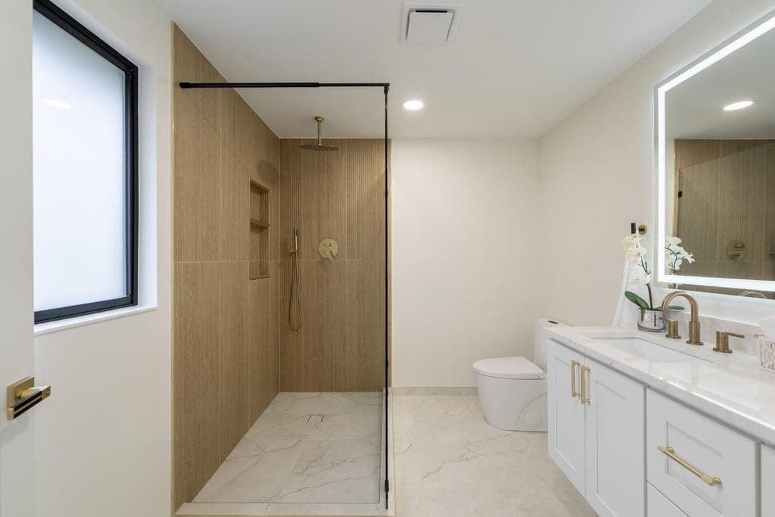 Walk-in shower with wood-look slat tile walls, marble-look floor, and brass fixtures