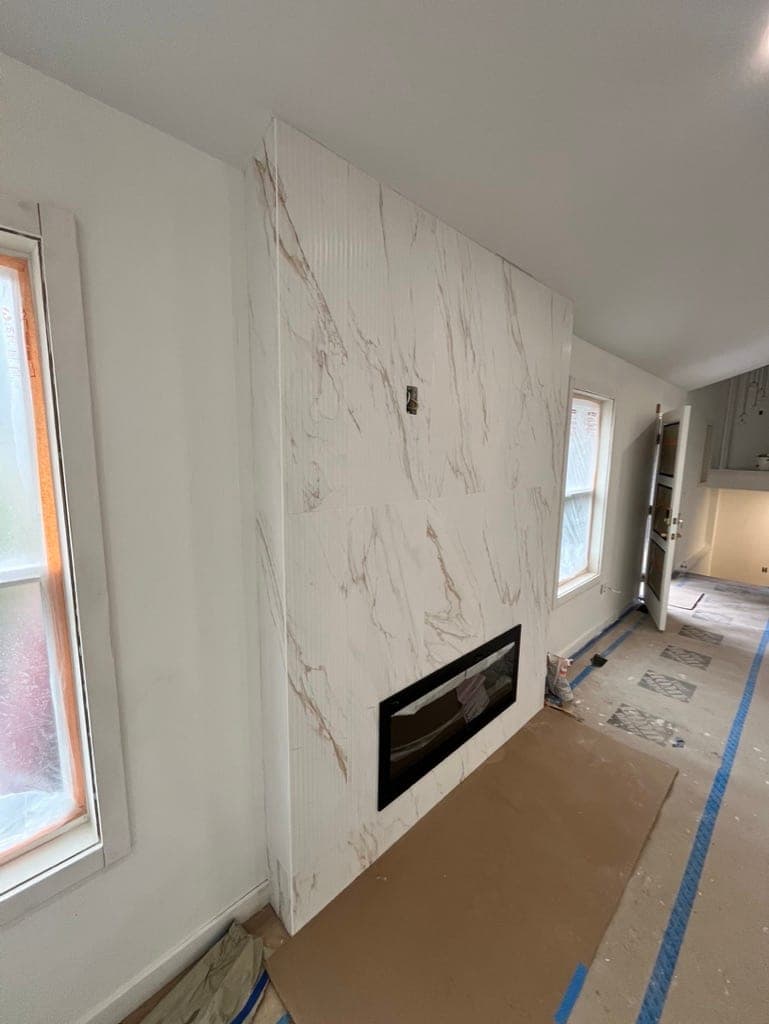 The same fireplace wall mid-install with the firebox cut in and floors still covered